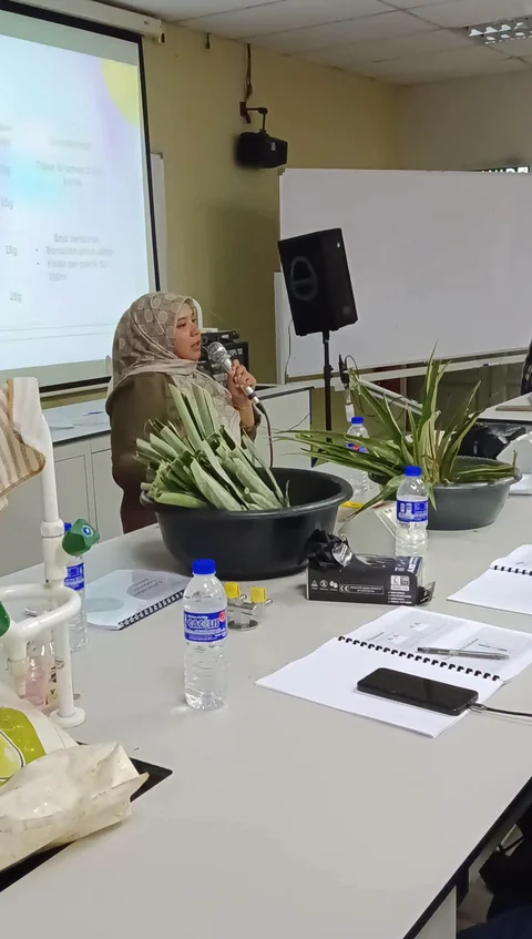Pengajar menerangkan latihan tanaman dengan bahan tumbuhan di meja.