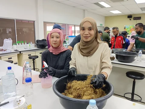 Dua peserta menyediakan bahan latihan di meja makmal.